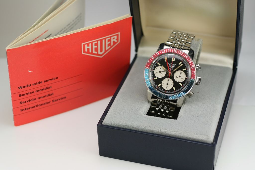 This is a vintage Heuer Autavia GMT with a blue/red bi-directional rotating bezel, three chronograph registers, pump pushers, and red hand with yellow arrow GMT hand. Retailed by Gubelin.