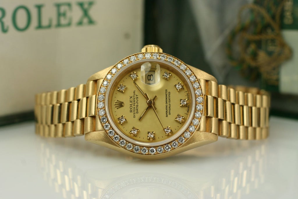 Lady's Rolex Date Just in yellow gold with champagne diamond dial, pave set diamond bezel, on a Rolex Presidental yellow gold bracelet. Comes with original papers, hand tags, and yellow gold fluted bezel.