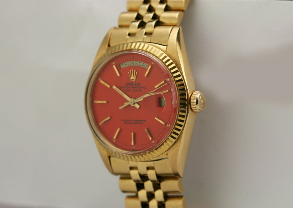 This is a Rolex 18k Day-Date President, Ref. 1803, with an orange enamel Stella dial. The Stella dials are extremely rare and limited because Rolex did not produce many of them.