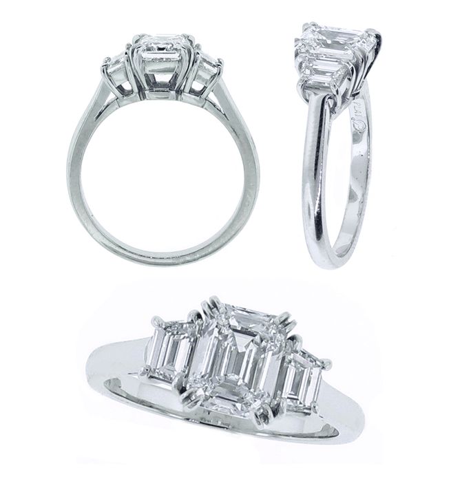 The ring features a center cut corner emerald cut diamond weighing 1.51 carats. The diamond is D color ans VS2 clarity. Set on either side are trapaziod cut diamonds weighing .70 carat
Diamond settings are custom designed and handmade in Washington