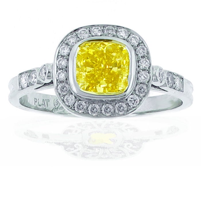 The ring features a spectacular cushion cut natural fancy intence yellow diamond weighing 1 carat. The ring was carefully designed to highlight the dimonds deeply saturated color and radient brilliance. The ring is set with twenty six round dimonds