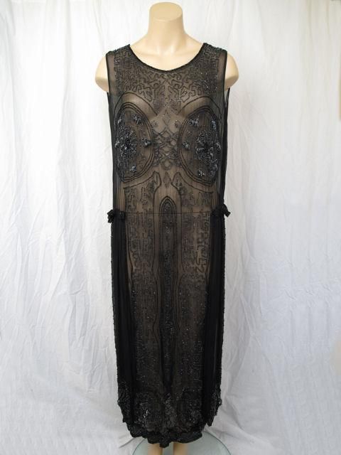 This is a black silk 1920's flapper dress.<br />
* It's covered in shiny black glass beads.<br />
* It has a ruffled detail on each hip with added side panels.<br />
* It's unlined and slips over the head to wear with hidden side snaps.<br