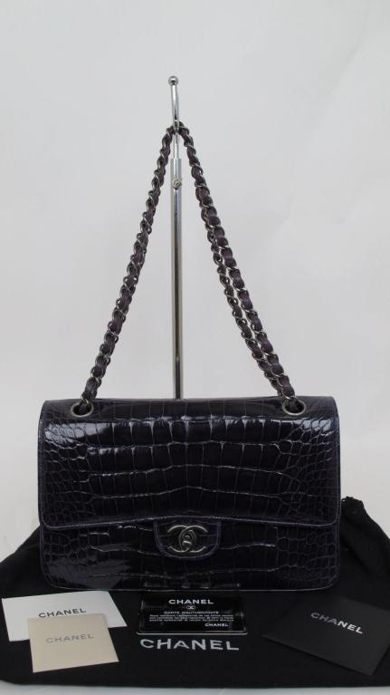 Here is this rare 100% authentic stunning Chanel classic double flap bag.

* It's made of amethyst alligator with gun metal hardware throughout.
* It has an open pocket on the back.
* The interior is lined in matching amethyst leather with an