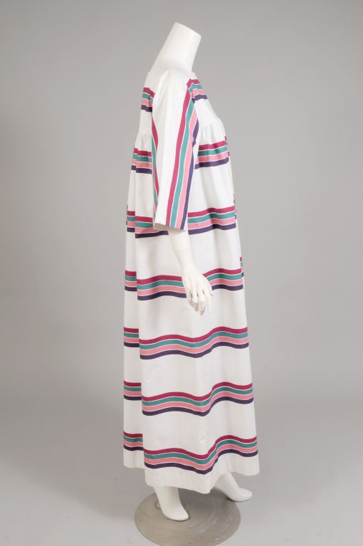 This fabulous caftan from Marimekko for Design Research in 1974 was designed by Pentti Rinta in the Liidokki dress pattern. Rows of colorful stripes enliven the bright white cotton.  The dress slips on over your head and it comes with a matching