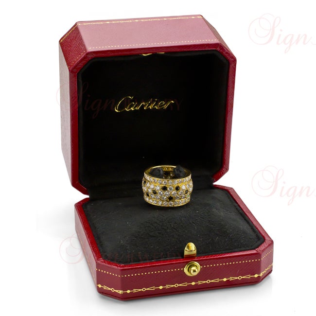 An authentic Cartier ring featuring the famous Panther design in 18k yellow gold. Made in 1988, this 5-row band is pave-set with natural white diamonds and accented with cabochon black onyx stones in the uniquely emblematic feline fashion of