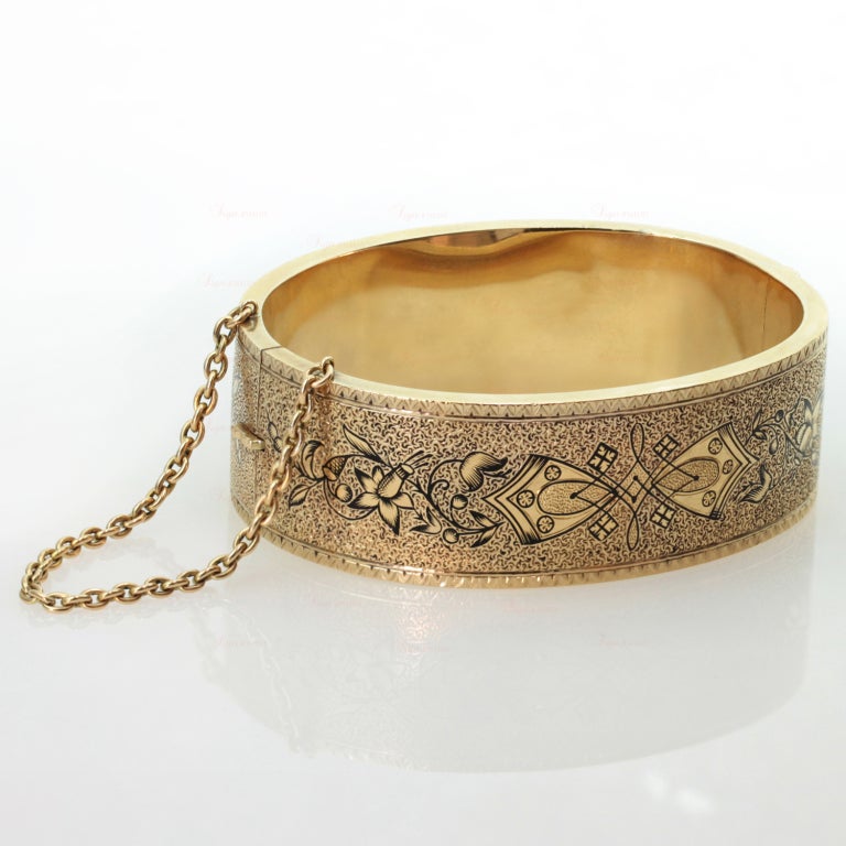 A fabulous antique bangle from the late Victorian era (1885 - 1901). This bracelet features an elegant black enamel ornamentation with exquisite decorations of textured 15k yellow gold. Completed by safety chain. A timeless design and a comfortable