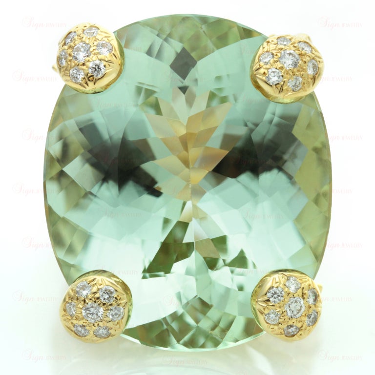 This fabulous ring from Christian Dior is made in 18k yellow gold and features a magnificient 23.0mm x 27.0mm oval light green faceted green aquamarine of an estimated 35 - 40 carats. The shank and the setting are beautifully accented with sparkling