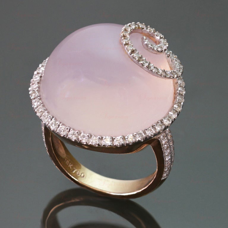 This modern women's cocktail ring is made in 18k yellow gold and features a round 20.0mm cabochon pinkish lavender quartz accented with a swirl design of sparkling diamonds with a total 113 round H-I VS2-SI1 diamonds of an estimated 1 carat. Chic