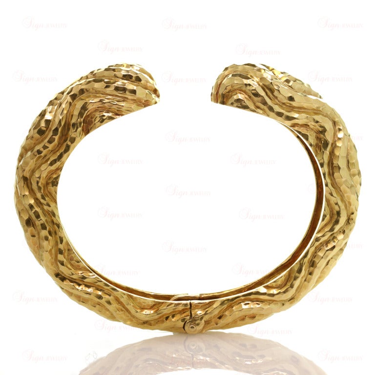 This stylish pair of David Webb's hinged bangle bracelets features captivating hammered textures made in 18k yellow gold. A fabulously chic design.