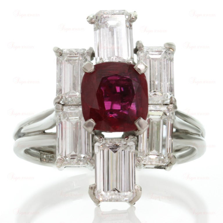 This elegant vintage ring is made in fine platinum and features a vivid sparkling red 6.0mm x 6.5mm faceted oval ruby of a about 1.08 carats surrounded by an estimated 3.90 carats of E-F color VVS clarity emerald-cut diamonds. Ring size is 5.25 - EU