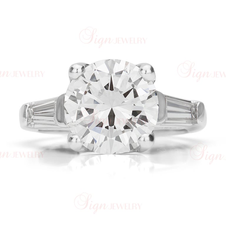 Give your sweetheart the gift of a lifetime. This stunningly romantic engagement ring is crafted out of platinum and features a prong-set round brilliant cut diamond center stone totaling 3.92 carats and two baguette-cut side stones totaling