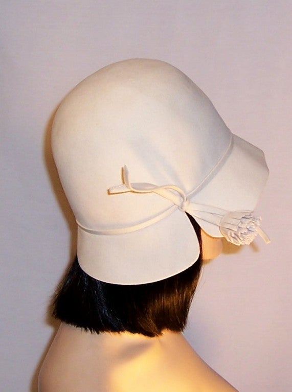 This is a wonderfully simple white woolen felt cloche-style hat quite reminiscent of a 1920's cloche hat, designed by Frank Olive. The cloche is tight-fitting, covering the head from the back of the neck and worn pulled down over the forehead.  This
