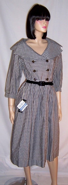 This is a fresh and crisp, 1950's vintage, new old stock with tags attached, shirt waist black and white checked dress with a full sailor's collar, double breasted buttoned bodice, black patent leather belt, and a full skirt.  The dress is marked a