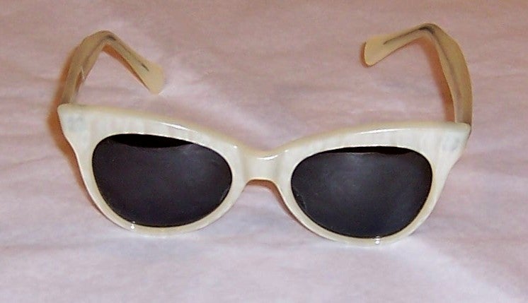 This is a fantastic pair of exceptionally well made white pearlized sunglasses dating from the late 1950's to the early 1960's. They are in excellent vintage condition and are marked, but the marking is not completely discernable.

Please contact