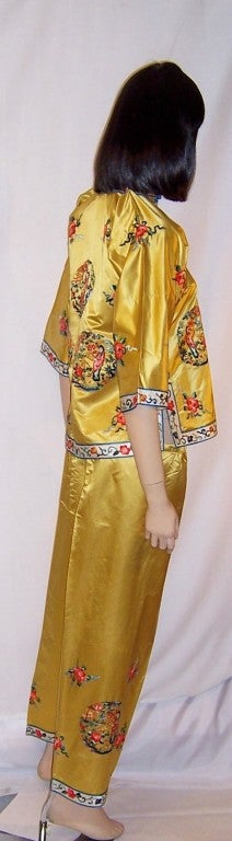 This is a lovely soft gold silk, Chinese hand-embroidered jacket and matching pants ensemble.  The jacket consists of six figural roundels interspersed with florals, four teal frog closures, and white silk embroidered trim around the collar, front,