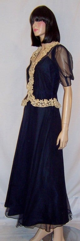 This is an elegant and gorgeous navy silk chiffon gown with short, poufy sheer sleeves, a fitted bodice, a collar and waist line trimmed in ecru lace designed by Sally Milgrim.  Sally Milgrim had been known for her exquisite evening wear and was one