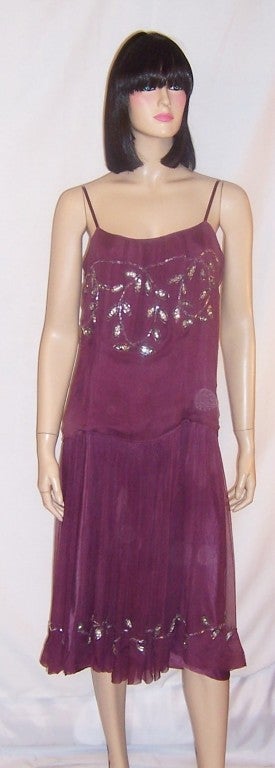This is a lovely, mauve silk chiffon dress with spaghetti straps, a loose fitting bodice, and a dropped waist line.  The dress is lined in mauve silk and must be slipped over one's head to be worn.  The silver bead work designs depict stylized