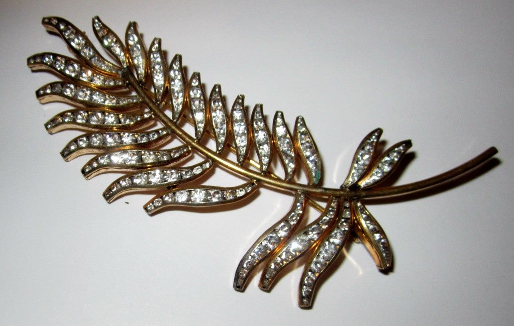 This is a simple and very elegant gold-toned metal leaf brooch embellished with clear rhinestones.  It measures 3.5