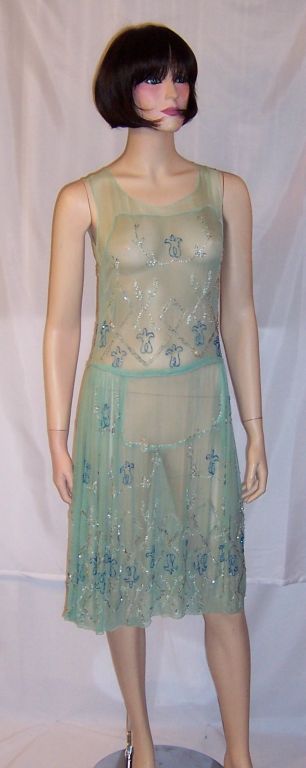 This is a lovely original 1920's springtime, mint green chiffon flapper dress with turquoise and silver beadwork designs. It is in good condition , but not mint condition.<br />
It has a tiny faint red spot on the bodice and two or three faint