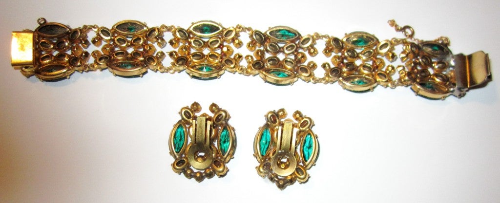 This is an exquisitely detailed Austrian bracelet and earring set comprised of emerald-colored and clear crystals on a gold-tone base. The stones are vibrant and striking and each is prong-set. The bracelet measures 7
