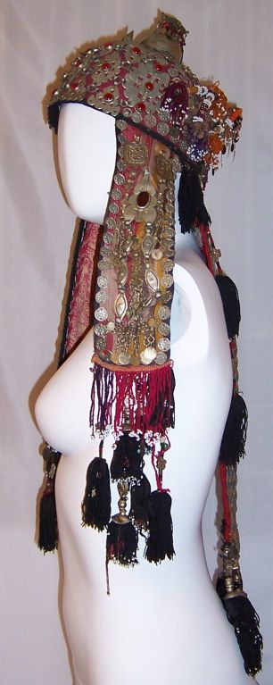 This is a rare and unique Afghani wedding headdress. It is comprised of many different materials including metal coins, tassels, glass beads, and fabric pieces.