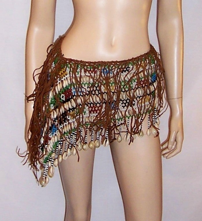 Offered for sale is this authentic women's tribal African loin cloth/skirt made of leather, multi-colored beads, and cowrie shells  The cowry or cowrie shells figure prominently in many West African cultures as a sign of fertility.  Waistbands of