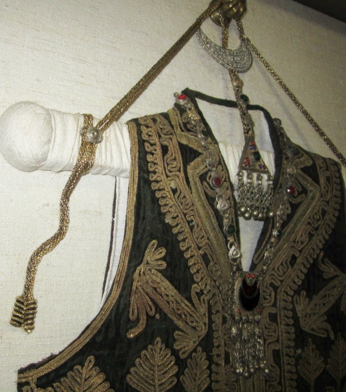 This is an antique, museum quality, Pakistani vest with heavy gold embroidery and jewel-like adornments and  embellishments, which has been masterfully framed under glass. The ornate wooden frame in silver-tone measures 26.25