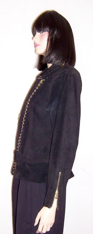 This is a simple and dramatically designed black suede jacket with an asymmetrical zippered closure, a zippered pocket diagonally placed, and a zippered cuff at either side. All zippers and the collar are further embellished with tiny studs. The