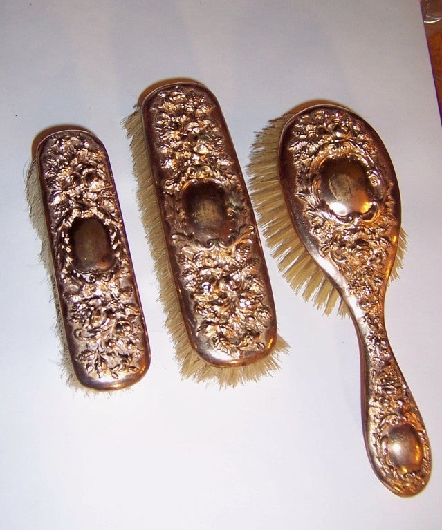 Offered for sale are three, turn-of-the century, gold-washed vanity brushes each marked 