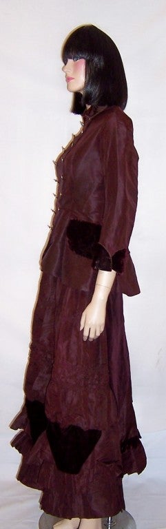 This is an unusual and handsome Victorian aubergine silk and velvet ensemble consisting of a fitted jacket and floor length skirt.  The upper interior lining of the bodice of the jacket and the upper waist band and top portion of the skirt have been