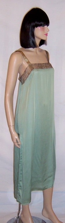 This is a superb example of early 1920's, unlabeled couture design executed in gold metallic lace, most probably French, with a teal green silk under slip, over a modified tabard-styled bodice, with a low slung teal green sash around the hips