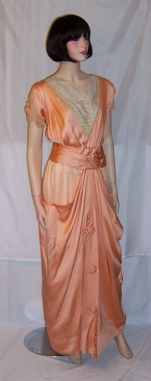 This is an extraordinarily beautiful Edwardian (1890-1910)apricot charmeuse and silk chiffon gown with many hand-sewn details. The gown has capped sleeves with each sleeve being embellished with a rosette. The waist is fitted and the waistband snaps