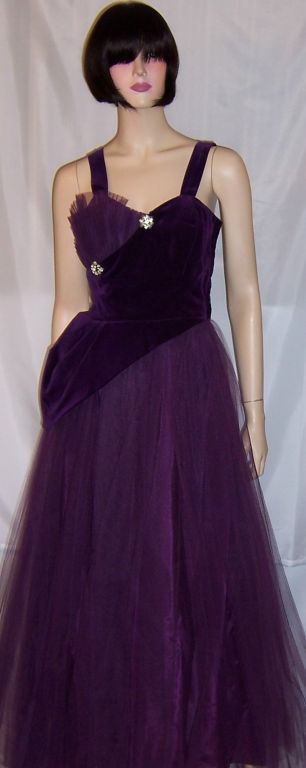 This is a gorgeous and striking, 1950's vintage, violet tulle and velvet ball gown. The gown has a taffeta underslip, layers of tulle, a boned bodice, and a side zipper for closure. The violet velvet crosses over the bodice and forms a modified