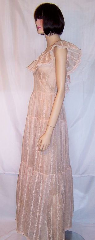 This is a sweet and feminine 1930's springtime gown made of the palest of pink organdy and embroidered with lines of tiny florets. The gown is sleeveless and has a modified yet somewhat fitted empire waist. The neckline is encircled by a lovely