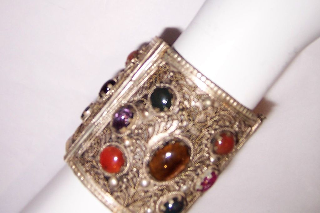 This is a wonderfully large ethnic cuff bracelet with filigree work and semi-precious stones in silver metal. The cuff is not marked nor signed and is approximately 3