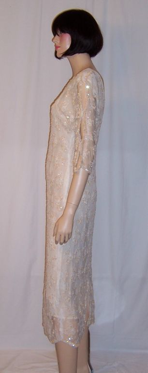 This is an exquisitely beautiful soft white, 1970's vintage, beaded, sequined, and lace sheath dress designed by Oleg Cassini. Cassini was probably most famous for having been appointed Jacqueline Kennedy's personal designer.<br />
This sheath