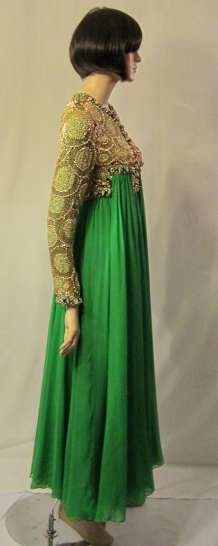 This is an opulent and luxurious kelly green chiffon gown with an elaborately beaded, sequined, and jeweled bodice and sleeves designed by William Travilla. Travilla had been an American award winning costume designer for theatre, film, and
