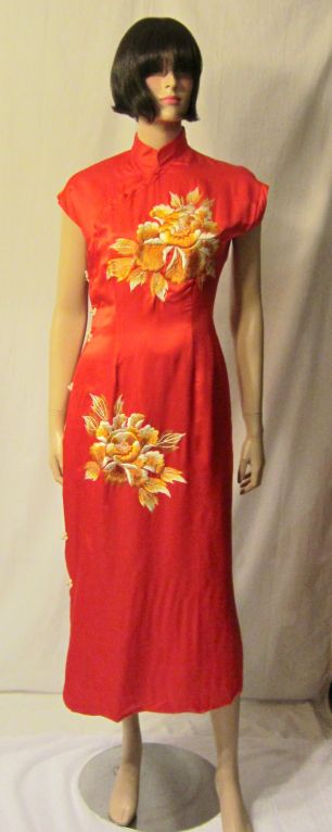 This is a stunning 1930's vintage red silk Chinese cheongsam hand-embroidered with large golden peonies. The gown has frog closures on the right side and snaps that run diagonally from the right side of the bodice to the neckline.The gown has a