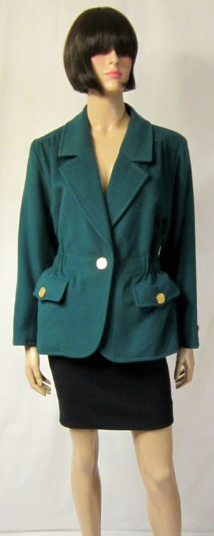 This is a stunning and stylish emerald green single-breasted jacket with a cinched waist and intricate brass button embellishments. The jacket is a size 34 EU and is in excellent vintage condition.