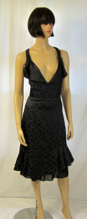 This is an amazingly beautiful midnight navy blue cocktail dress designed by Giorgio Armani with many fine details. The neckline is cut low, but is softened with a slight ruffle on each side. The waist is cinched with an embroidered waist band. The