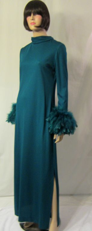 Victor Costa bought out his then partner in 1974 and began his own fashion house/label, Victor Costa LTD. This simply elegant floor length gown in teal blue with a wide band of matching feathers at each wrist, an attached bow at the neckline, and