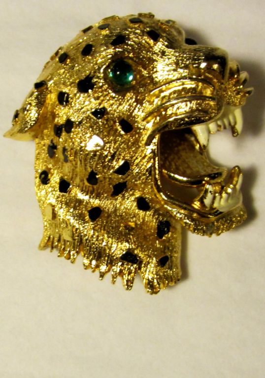 This is a ferocious and fierce leopard, brooch made of gold-toned metal with black enameled spots and white teeth. The eyes are green cabachon stones. The brooch measures 1 1/2