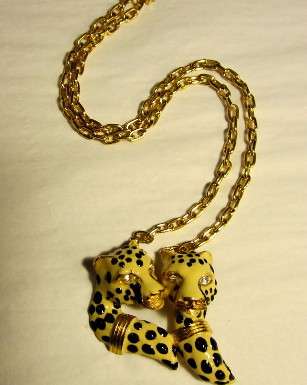 This is an unusual double leopard head pendant with black and cream-colored enamelwork, gold-toned accents, and clear rhinestone eyes. The chain measures approximately 11