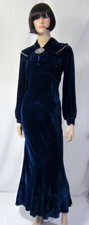 This is a luxurious royal midnight blue silk velvet gown, of the 1930's vintage, with a yoke which surrounds the neckline and is attached to the bodice of the gown with gold metallic thread and fine stitching. The gown has snaps on the left side for