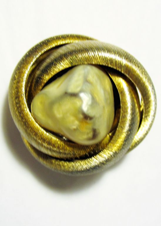 This is an unusual gold-toned brooch with a large faux pearl encircled by metal roping, designed by Arnold Scaasi in the 1960's, I believe. Scaasi was Canadian born as Arnold Isaacs, which is Scaasi spelled backwards. The brooch measures 1 1/2