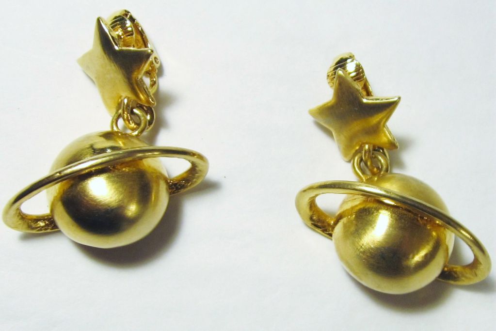 This is an unique and fanciful pair of brushed gold-toned earrings, unmarked, with the planet, Saturn and its rings, hanging from a star. Each earring measures 1 1/2