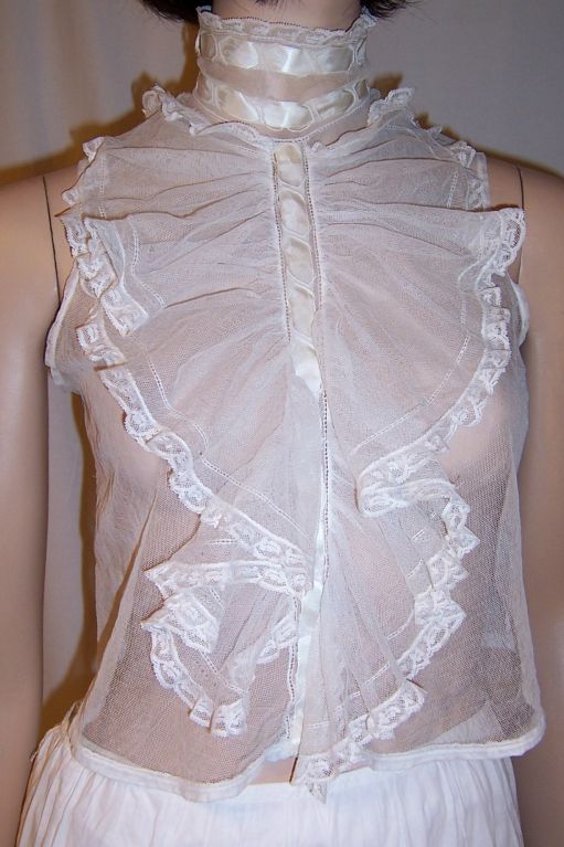 This is a gorgeous Victorian sleeveless jabot made of fine English netting with cascading ruffles of netting edged in Valenciennes lace. The original stay is still in the back collar. It has a high mandarin collar and the jabot and collar have been