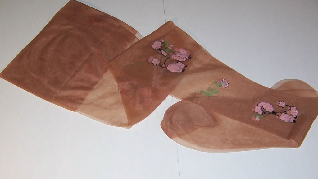 This is a fanciful pair of 1950's nylon stockings, hand-painted with pink poodles and floral sprays. The pair is in excellent vintage condition, never before worn, and the foot of each, from toe to heel measures 9