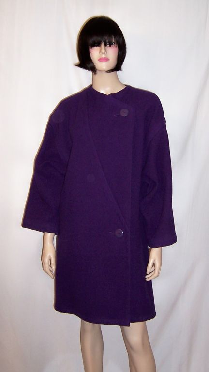 This is a fabulously striking and comfortable aubergine/eggplant woolen coat designed by Mariuccia Mandelli who founded the company, Krizia, in the early 1950's. The coat is collarless, has sloping shoulders, two buttons for closure, and an