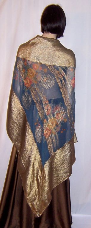 Offered for sale is this exquisite 1920's Art Deco triangular shawl of Prussian blue and orange florals with gold lame accents and a wide band of gold lame edging the shawl. The shawl measures 76